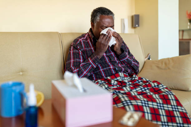Patient with flu on couch holding tissue to nose