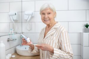 senior woman holding toothbrush maintaining personal care