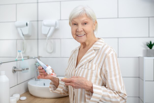 senior woman holding toothbrush maintaining personal hygiene